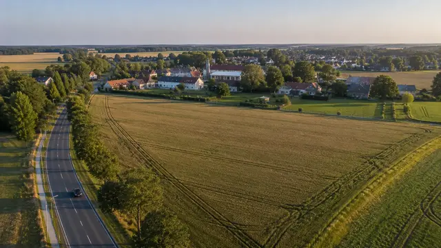 Luftaufnahme des geplanten Wohngebiets an der Jüterboger Allee in Mügeln mit angrenzenden Feldern, bestehender Wohnbebauung und ländlicher Umgebung im Landkreis Wittenberg.