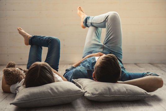Haus-Familie-Wohnen-Serie-12-26 Vater und Tochter liegen zu Hause auf dem Fussboden.