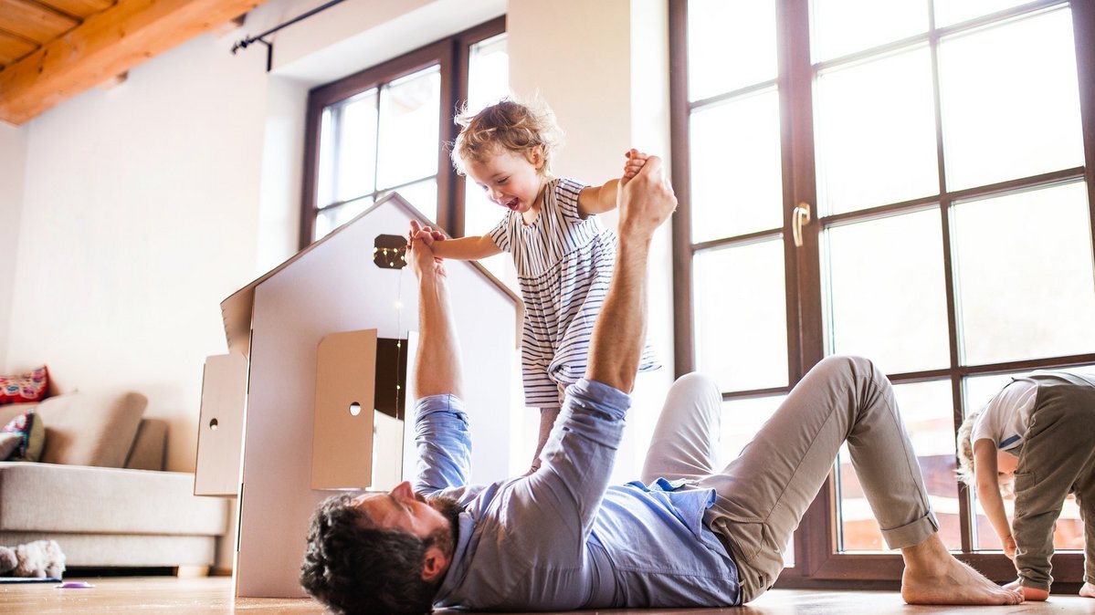 Familie spielt im eigenen Zuhause als Symbol für zukunftssicheres Wohnen und moderne Hausplanung