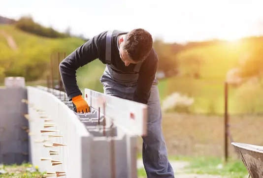 Maurer arbeitet am Mauerwerk für ein Haus. Energieeffiziente Bauweise mit moderner Dämmung für nachhaltige Massivhäuser.