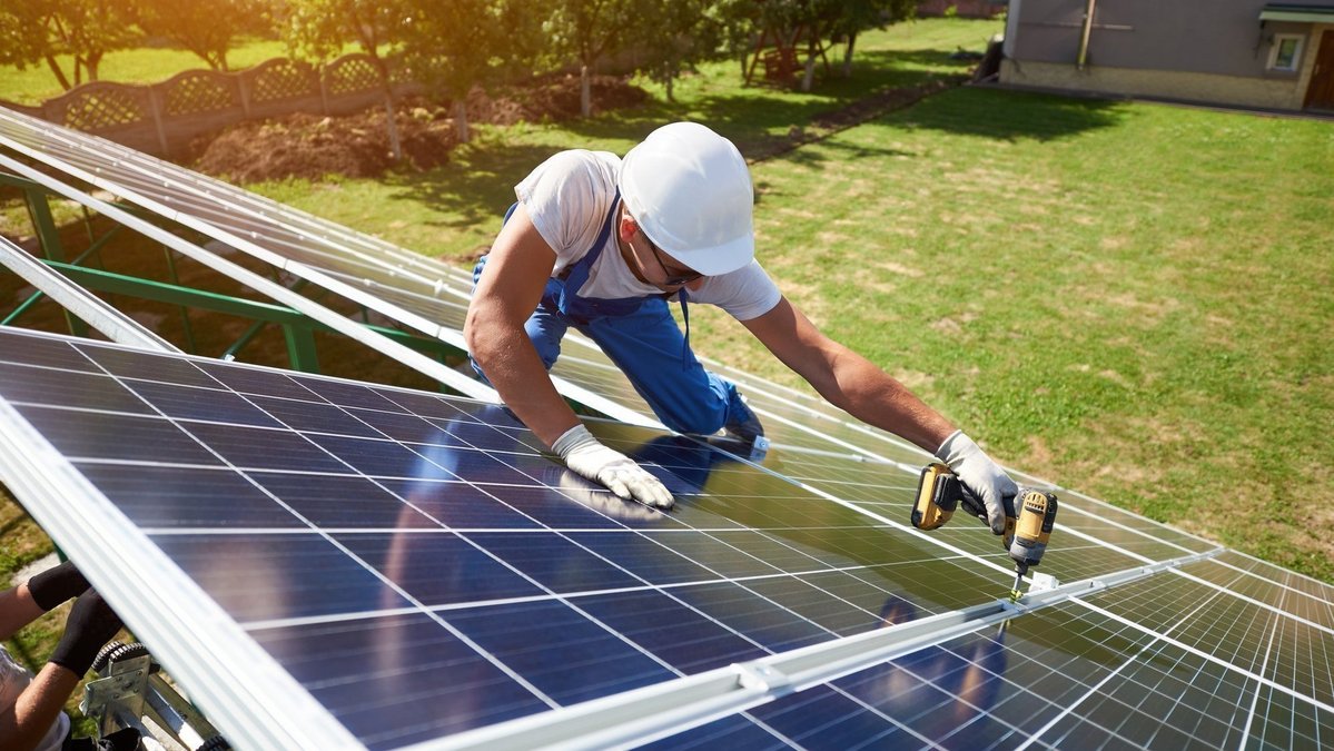 Handwerker montiert Photovoltaikanlage auf einem Dach für energieeffizientes Wohnen