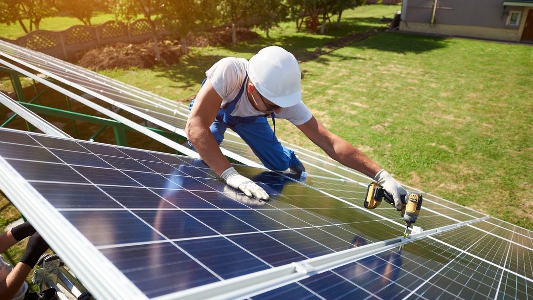 Handwerker installiert Solaranlage auf Hausdach bei sonnigem Wetter