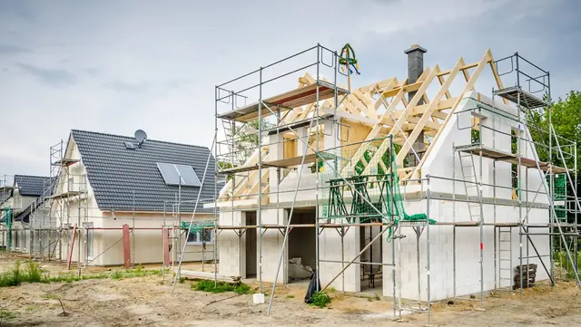 Zwei Massivhäuser in der Aufbauphase auf einem großem Baugrund. Das vordere Massivhaus ist im Rohbau.