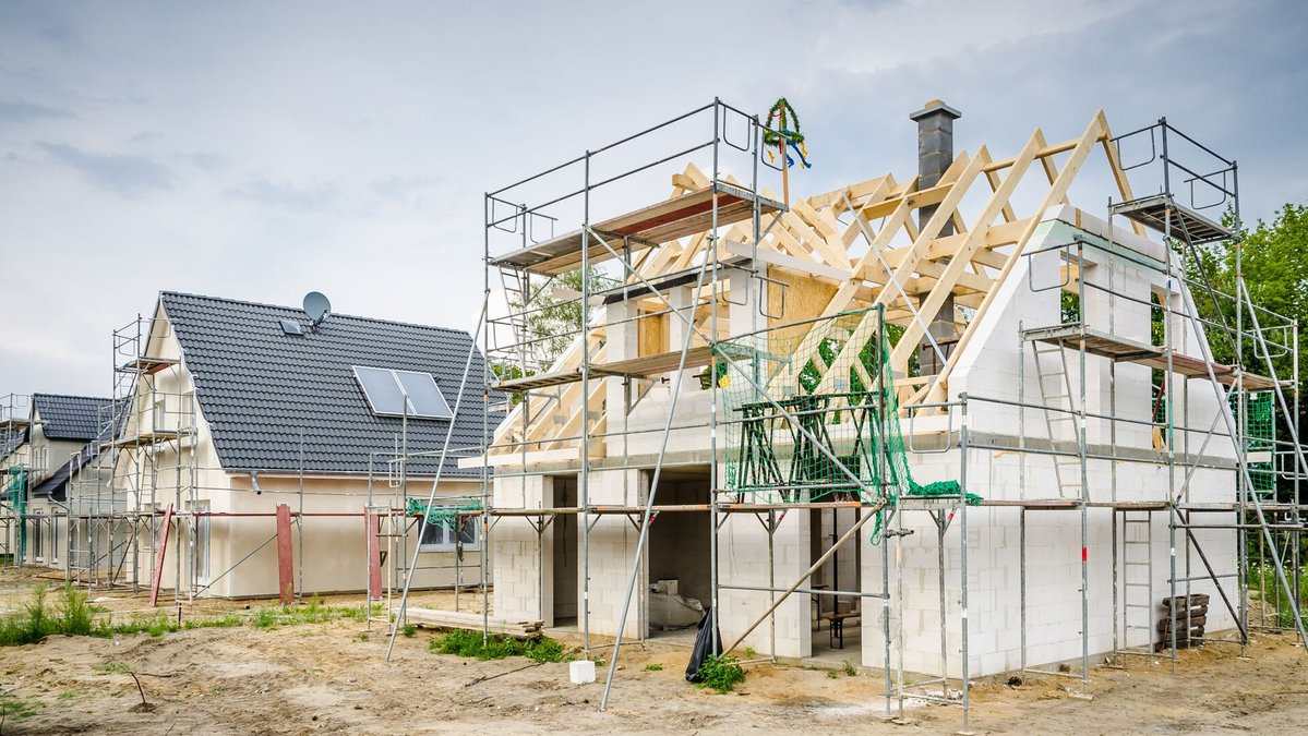 massiv-bauen-baustelle-haus-rohbau-01 Zwei Massivhäuser in der Aufbauphase auf einem großem Baugrund. Das vordere Massivhaus ist im Rohbau.