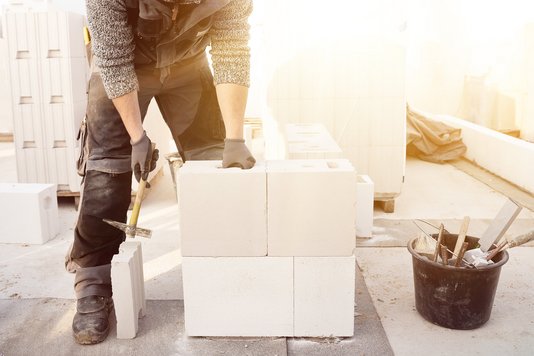 Handwerker fixiert Portenbeton für das Mauerwerk der Massivhäuser von Town & Country Haus.