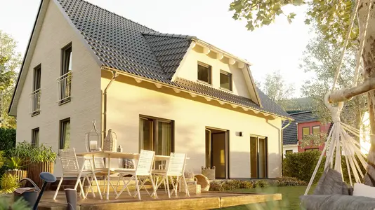 Freistehendes Einfamilienhaus mit grauem Satteldach, heller Fassade und großer Terrasse im Grünen mit Gartenmöbeln.
